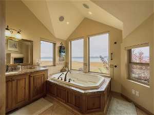 Bathroom with vanity, tile floors, a bathing tub, vaulted ceiling, and a water view