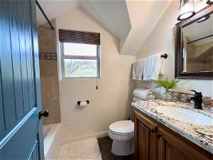 Full bathroom featuring tiled shower / bath, oversized vanity, tile floors, toilet, and lofted ceiling