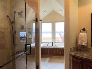 Bathroom featuring tile floors, vaulted ceiling, and plus walk in shower