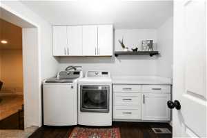 Clothes washing area with washer hookup, dark hardwood / wood-style flooring, separate washer and dryer, and cabinets