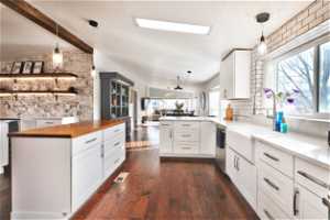 Kitchen featuring a wealth of natural light, dark wood-type flooring, backsplash, and kitchen peninsula