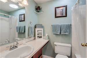 Full bathroom with vanity with extensive cabinet space, toilet, and shower / tub combo with curtain