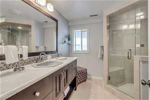 Bathroom featuring tile flooring, backsplash, an enclosed shower, and vanity
