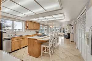 Kitchen with a breakfast bar, stainless steel appliances, a notable chandelier, sink, and a kitchen island