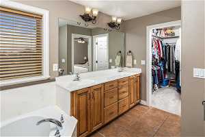 Bathroom featuring a washtub, tile floors, a notable chandelier, and double sink vanity