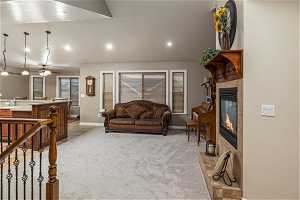 Living room featuring vaulted ceiling, light colored carpet, ceiling fan, and a tile fireplace