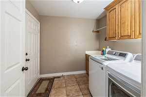 Laundry area featuring light tile floors, cabinets, and independent washer and dryer