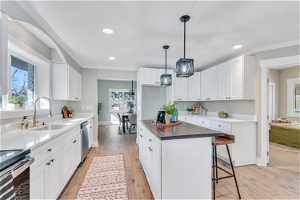 Kitchen featuring white cabinets, light hardwood / wood-style floors, pendant lighting, and a wealth of natural light