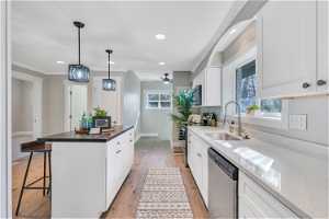Kitchen featuring stainless steel appliances, white cabinets, a breakfast bar, a center island, and ceiling fan