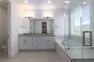 Bathroom with tile floors, a healthy amount of sunlight, tiled bath, and dual bowl vanity