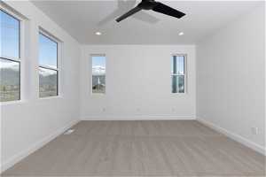 Carpeted spare room with a wealth of natural light and ceiling fan