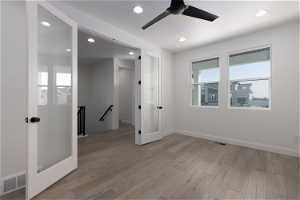 Spare room featuring light hardwood / wood-style flooring, ceiling fan, and a healthy amount of sunlight