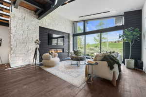 Living room featuring floor to ceiling windows, wood finished floors, and a glass covered fireplace