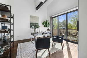 Office area featuring baseboards, a high ceiling, wood finished floors, and beamed ceiling