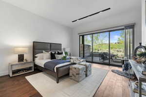 Bedroom with access to outside, lofted ceiling, and hardwood / wood-style floors