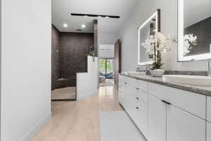 Full bath featuring double vanity, a walk in shower, recessed lighting, and baseboards