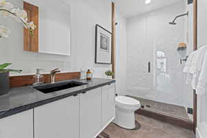 Full bathroom featuring toilet, vanity, recessed lighting, and a shower stall