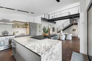 Kitchen featuring stainless steel appliances, extractor fan, a kitchen island, dark wood-style floors, and tasteful backsplash