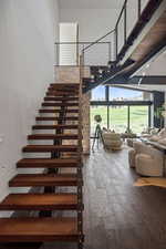 Stairway with wood finished floors and a towering ceiling