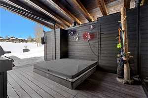 Snow covered deck with a covered hot tub