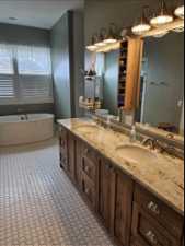 Primary Bathroom with a bath to relax in, tile floors, and dual bowl vanity with granite counters