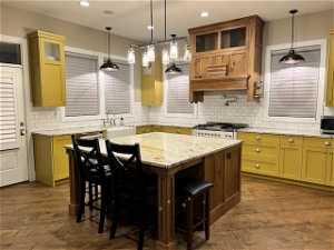 Kitchen with pendant lighting, a center island, a kitchen breakfast bar, and light stone counters
