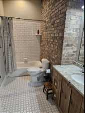 Main Floor Full bathroom with shower / bath combo with  vanity, brick wall, toilet, and tile flooring