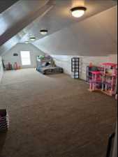 Rec room with lofted ceiling, carpet flooring, and a textured ceiling