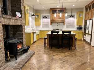 Kitchen featuring pendant lighting, stainless steel appliances, a kitchen island, and a wood stove