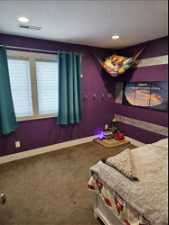 Bedroom with dark colored carpet and a textured ceiling