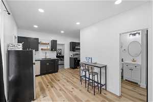 Kitchen featuring stainless steel appliances, light hardwood / wood-style flooring, a kitchen breakfast bar, and sink