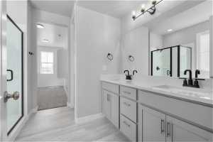 Bathroom featuring an enclosed shower, dual sinks, hardwood / wood-style flooring, and large vanity