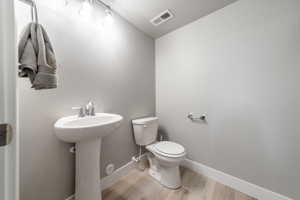 Bathroom with sink, hardwood / wood-style flooring, a textured ceiling, and toilet