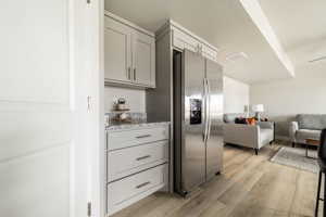 Interior space with light hardwood / wood-style flooring, stainless steel fridge, light stone counters, and gray cabinets