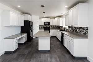 Kitchen featuring pendant lighting, white cabinetry, a center island, black appliances, and sink