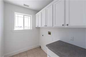 Clothes washing area with cabinets, washer hookup, light tile floors, and electric dryer hookup