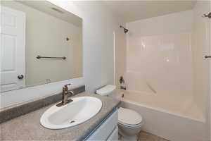 Basement with full bathroom with tub / shower combination, vanity, tile flooring, and toilet