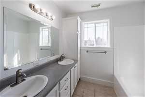 Bathroom with dual sinks, large vanity, tile floors, and  shower combination