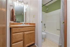 Full bathroom with toilet, large vanity, a textured ceiling, and bathtub / shower combination