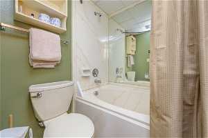 Bathroom with toilet, a paneled ceiling, and shower / bath combo with shower curtain