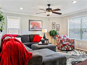 Living room with plenty of natural light, crown molding, and ceiling fan