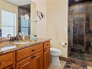 Bathroom featuring an enclosed shower, vanity with extensive cabinet space, tile floors, and toilet