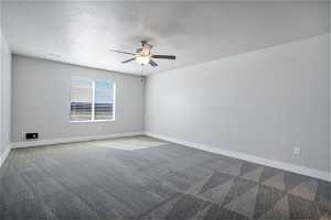 Spare room featuring light carpet, a textured ceiling, and ceiling fan