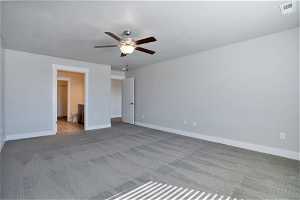 Unfurnished bedroom featuring dark carpet, connected bathroom, and ceiling fan