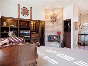 Living room featuring a fireplace, light carpet, an inviting chandelier, and brick wall