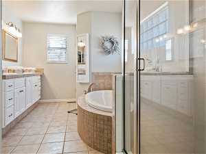 Bathroom with tile flooring, independent shower and bath, and vanity with extensive cabinet space