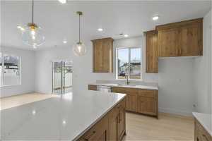 Kitchen with hanging light fixtures, light hardwood / wood-style flooring, sink, and light stone counters
