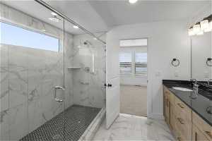 Bathroom with tile flooring, vanity with extensive cabinet space, a shower with door, and a healthy amount of sunlight