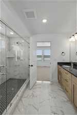 Bathroom featuring vanity, tile flooring, plenty of natural light, and a shower with shower door