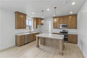 Kitchen featuring a center island, sink, pendant lighting, light hardwood / wood-style flooring, and stainless steel appliances